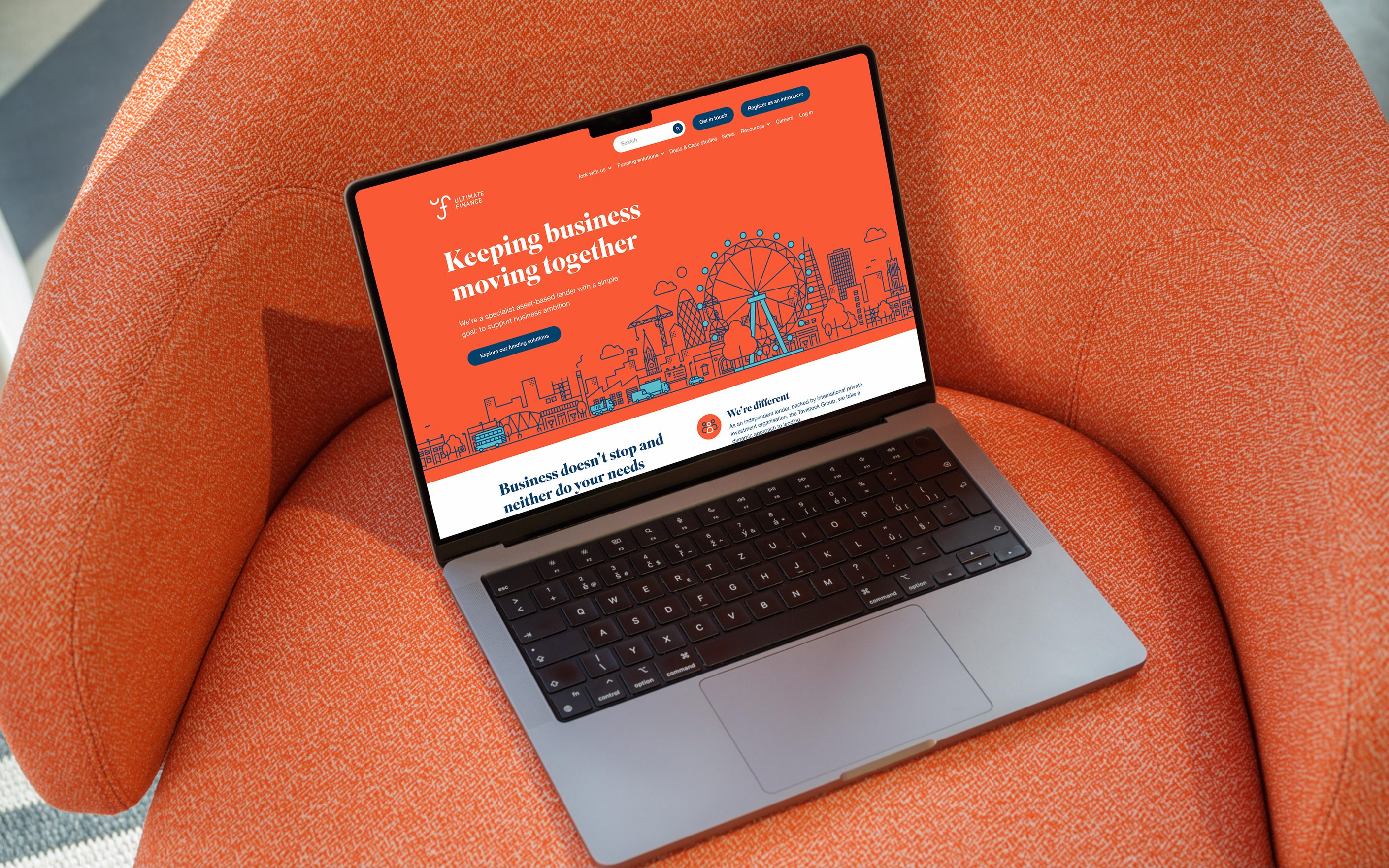 Laptop displaying Ultimate Finance website with orange design and "Keeping business moving together" headline on orange chair