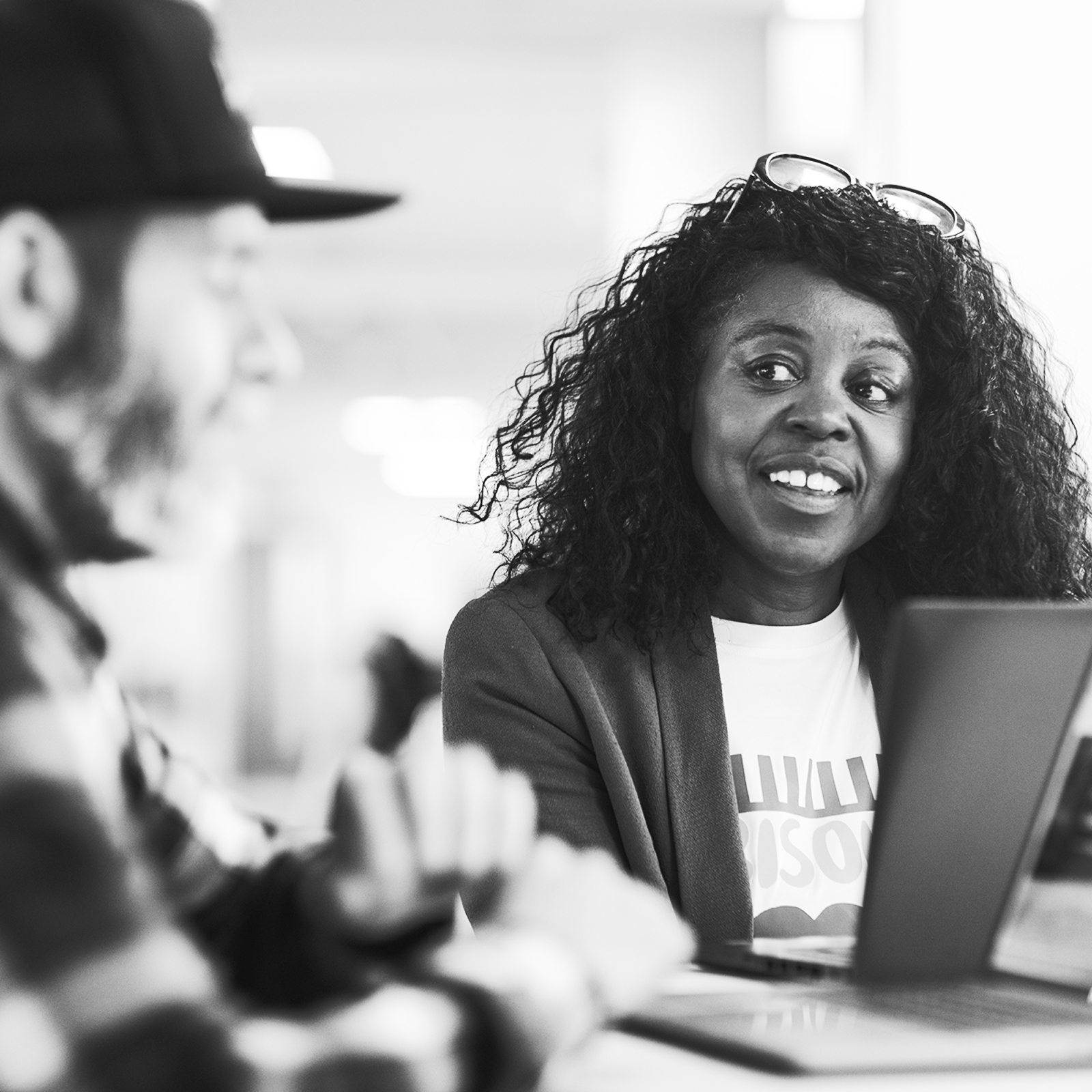 Smiling woman with curly hair working on laptop in modern office environment